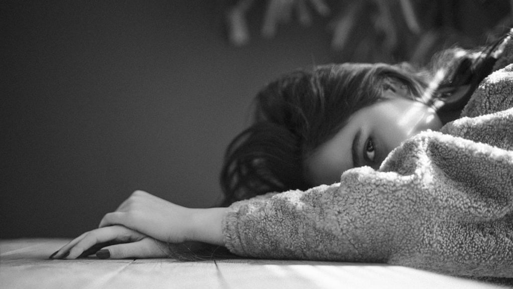 a young girl laying on a bed with her head on the pillow