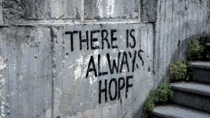 Graffiti on concrete wall reads 'There is always hope' next to outdoor stairs.